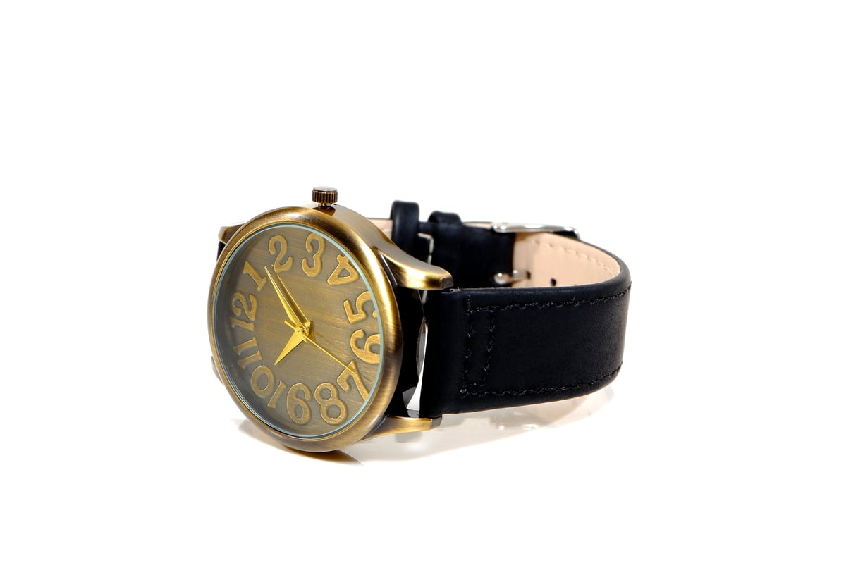 A luxurious brass watch with a sleek black leather strap isolated, elegance and sophistication