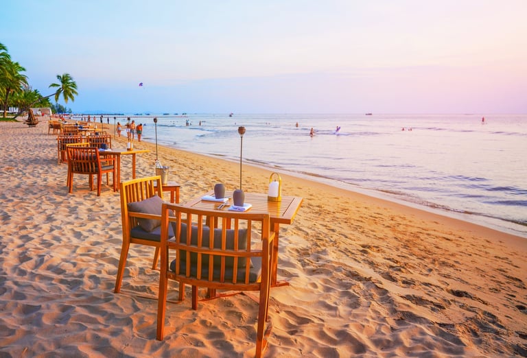 Table for dining on sand beach with sea view at sunset