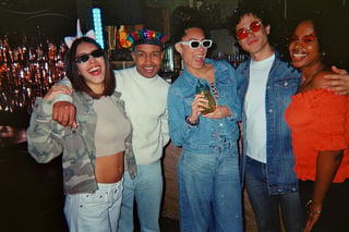 Diverse group of young adults smiling and posing together at a vibrant retro-themed party