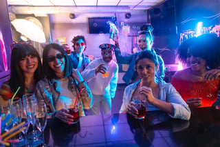 Friends enjoying drinks at lively nightclub with neon lights