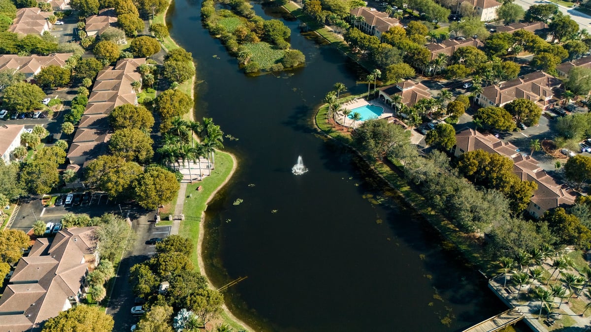 Suburban residential lake with villas and fountain seen from drone