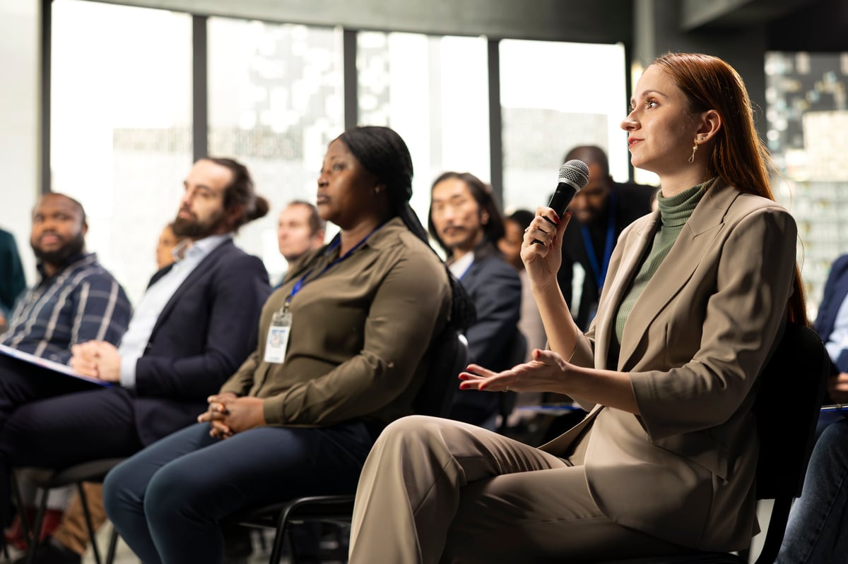 Young adult businesswoman in audience interacting with presenter