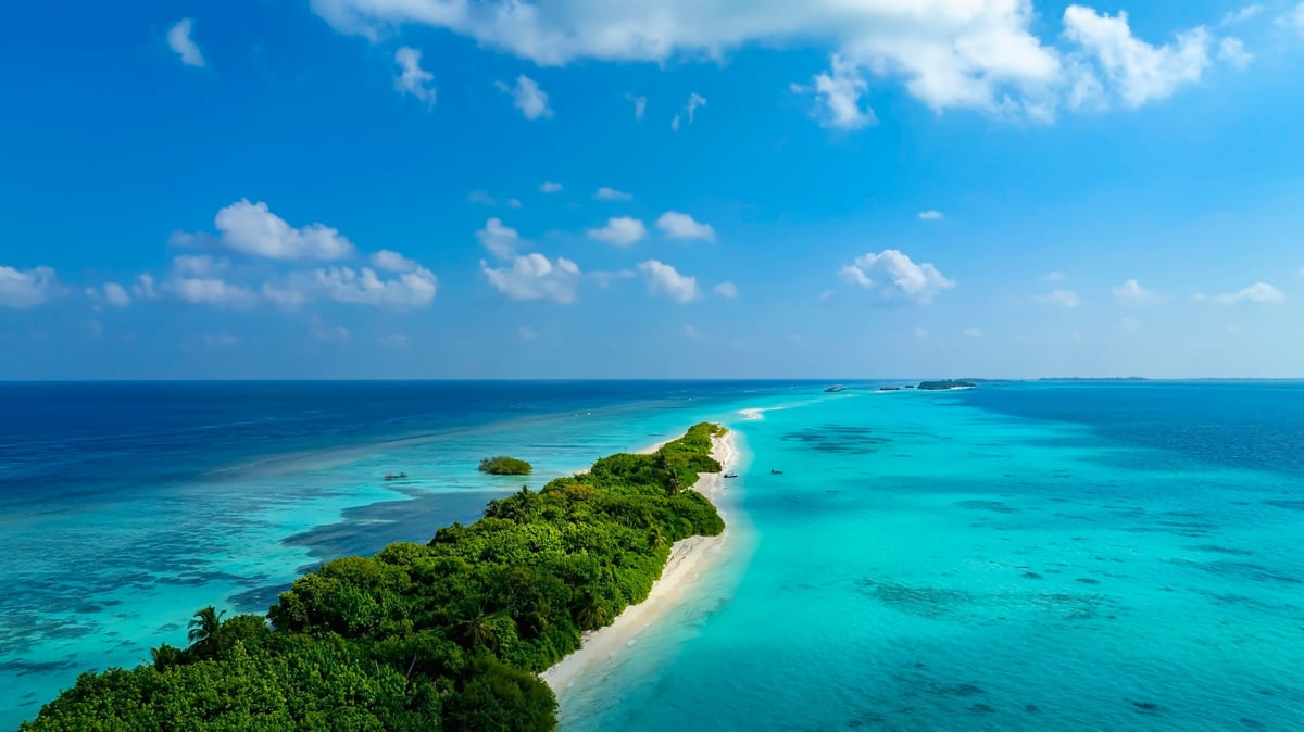 Aerial view of island with white sand beach coastline in Maldives
