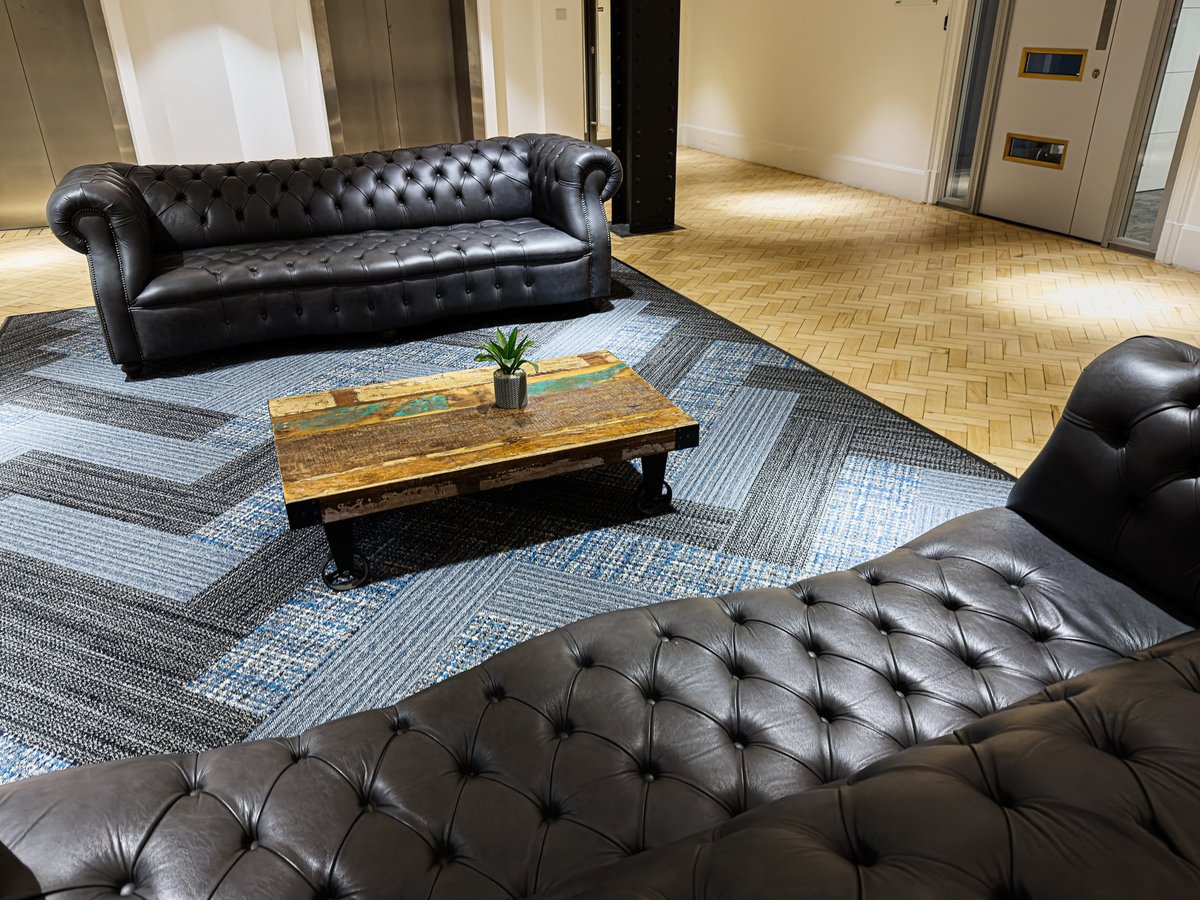 Stylish black tufted sofas and rustic coffee table create a welcoming business lounge setting