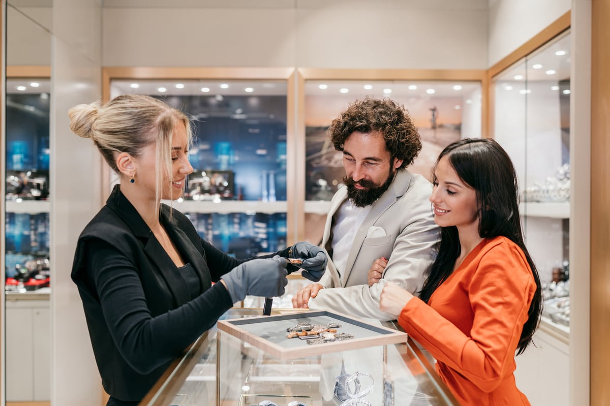 Elegant couple consulting with a saleswoman presenting a luxury watch in a high-end jewelry boutique