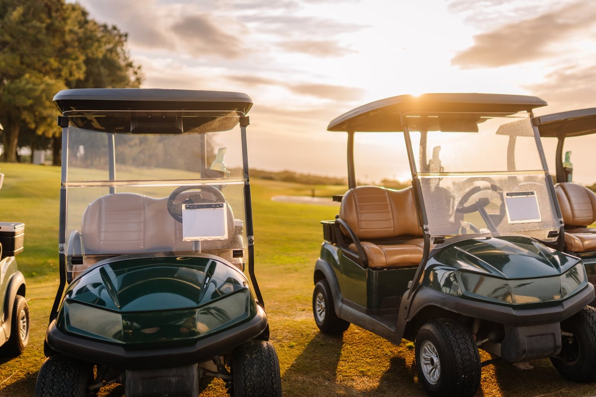 Two golf carts on a course at sunset with scenic fairway views