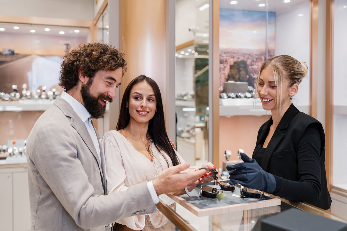 Elegant couple looking at luxury watches presented by a retail clerk in an exclusive jewelry store