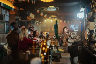 Varied group of buddies and a bartender are joyfully rooting for their team in a charming irish pub
