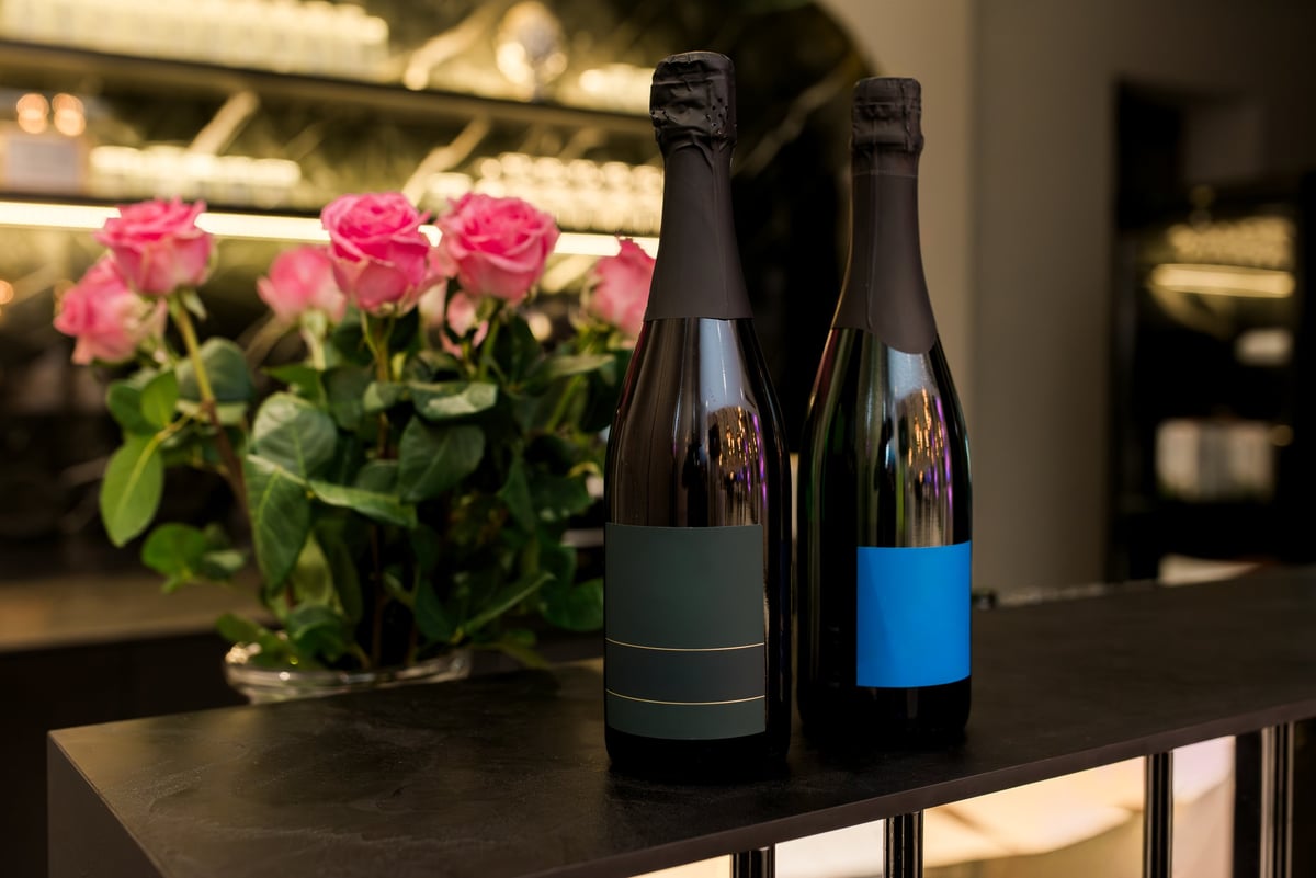 Two elegant sparkling wine bottles with minimalist labels and pink roses