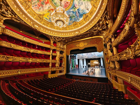 Paris,France-Oct.4th 2025: Wide-angle interior view of the Palais Garnier auditorium in Paris, featuring red velvet seats, ornate golden gilding, and the Chagall ceiling