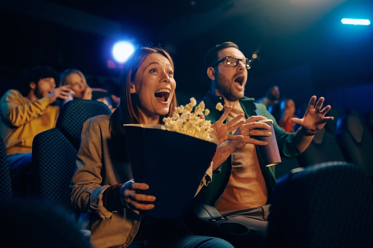 Happy couple feeling amazed with movie projection in theater