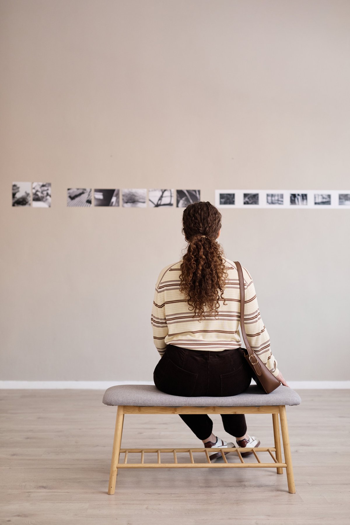 Person viewing contemporary art and photography displayed on walls in a gallery setting during Milan Design Week