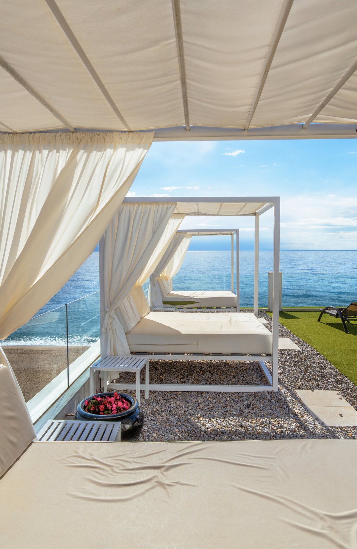 Luxury white cabins with sun loungers on a pebble terrace overlooking the blue Mediterranean Sea