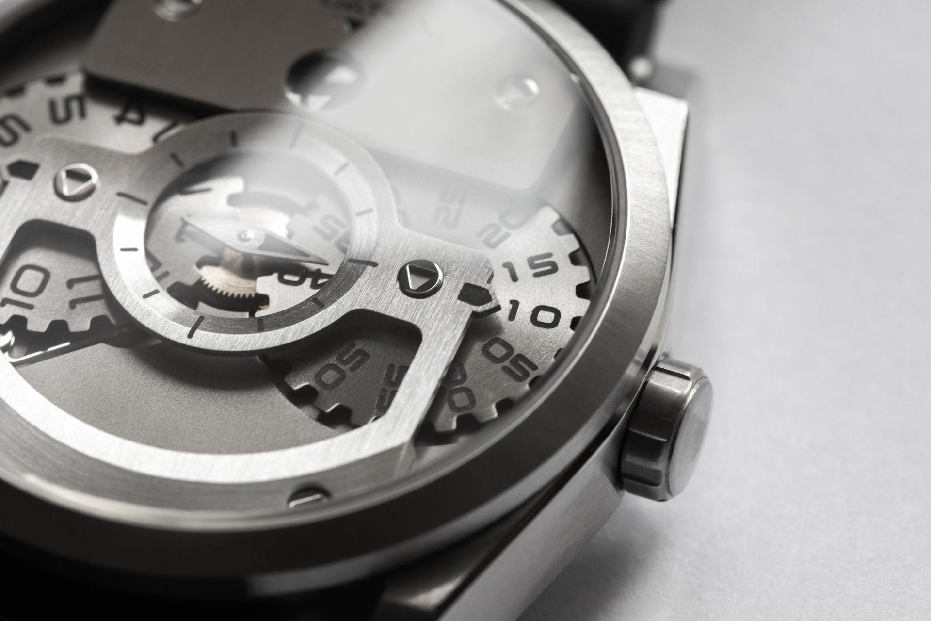 Macro view of a mechanical wristwatch revealing metal gears, numbered discs and a polished crown, evoking precision, craftsmanship and luxury timekeeping