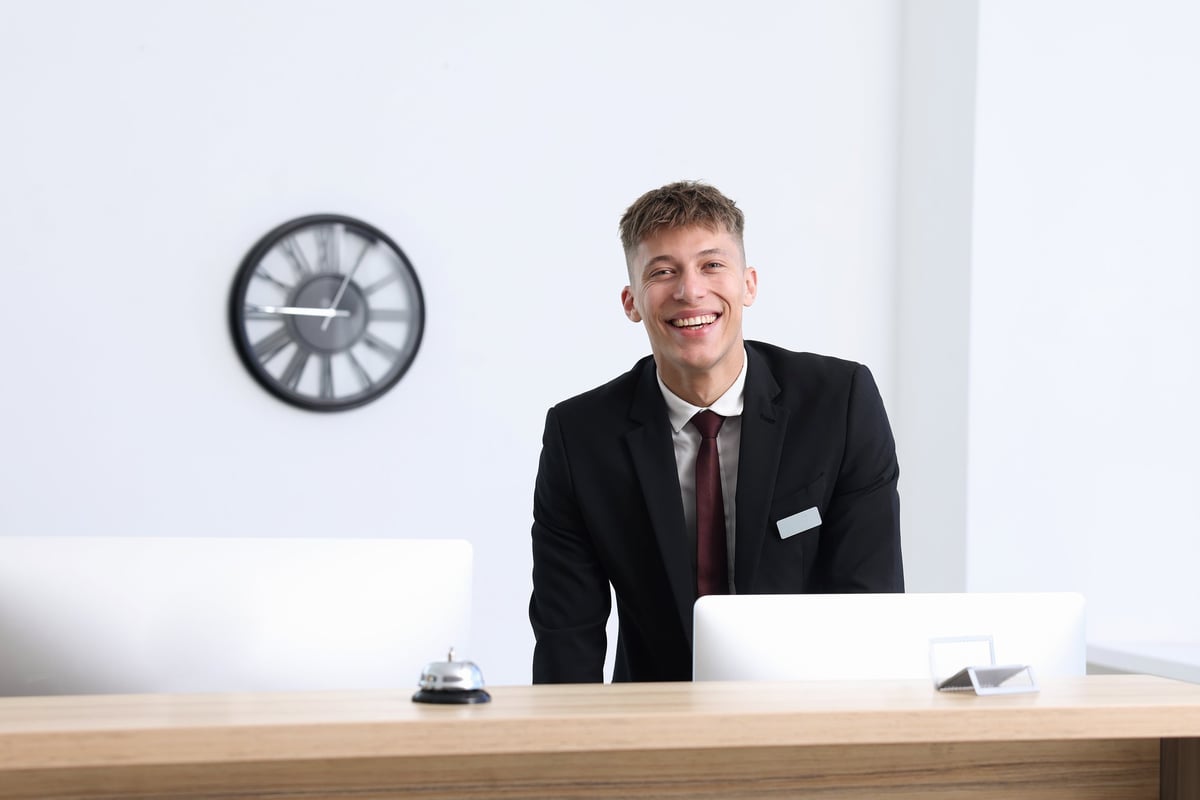 Receptionist in uniform working at reception desk indoors
