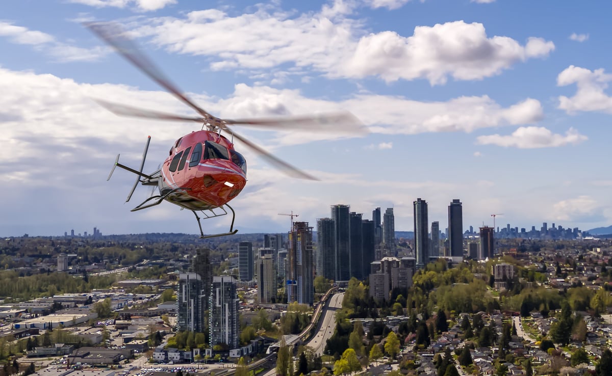 Vancouver city skyline featuring a red helicopter in flight above modern high-rises