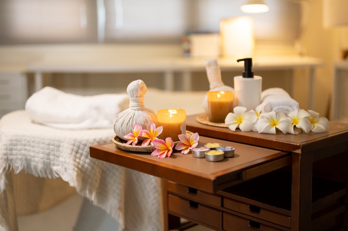 Spa massage room with herbal compress balls, candles, flowers and massage table