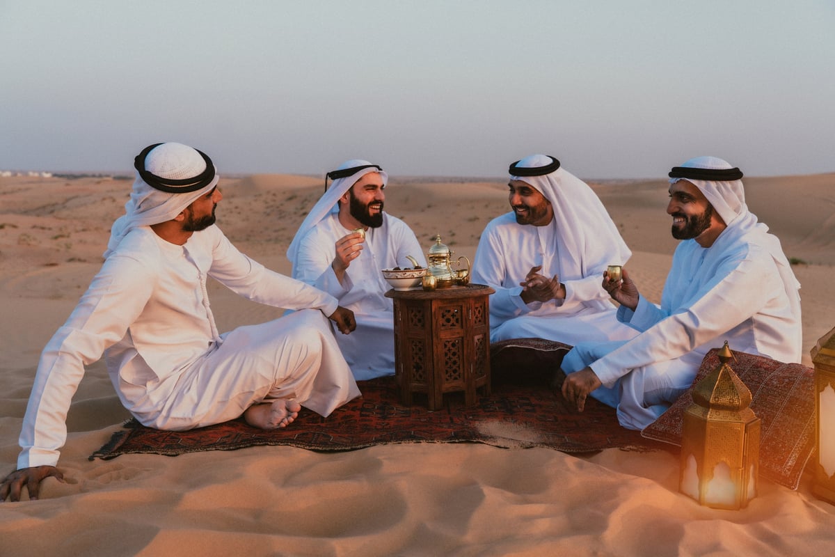 Emirati men in traditional kandura enjoying Arabic coffee in the Dubai desert