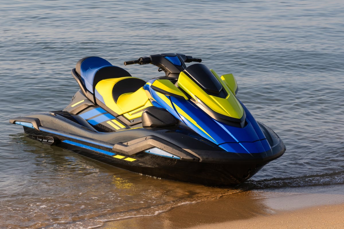 A vibrant blue and yellow jet ski parked on the sandy shore