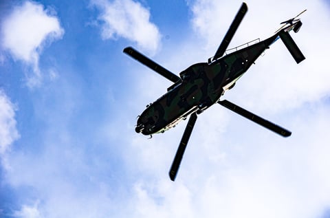 Low-angle view of helicopter in flight with blue sky