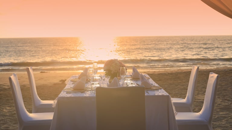 Romantic dinner table setting on the beach at sunset