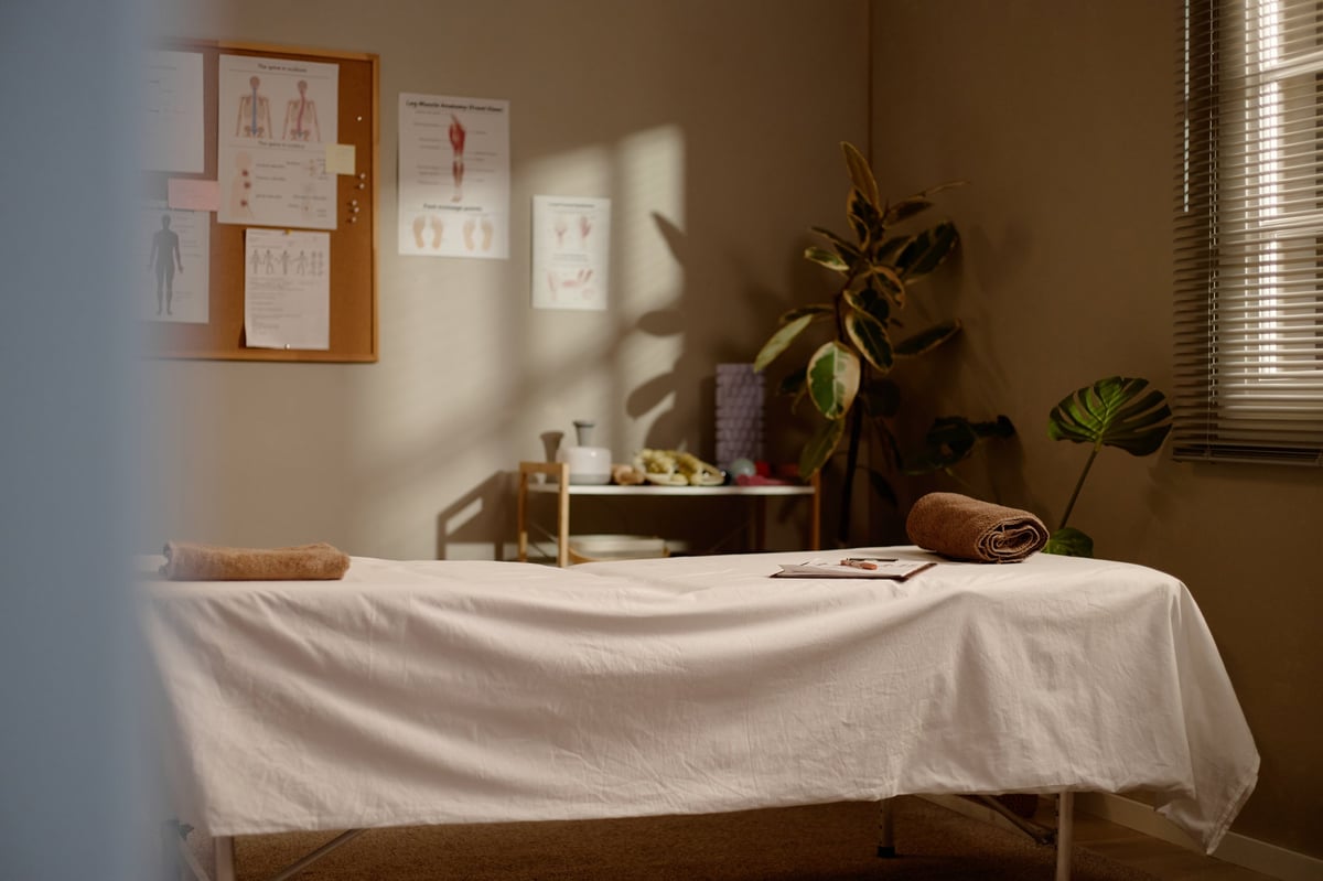Massage therapy room featuring treatment table, folded towels, preparing for wellness session and holistic care