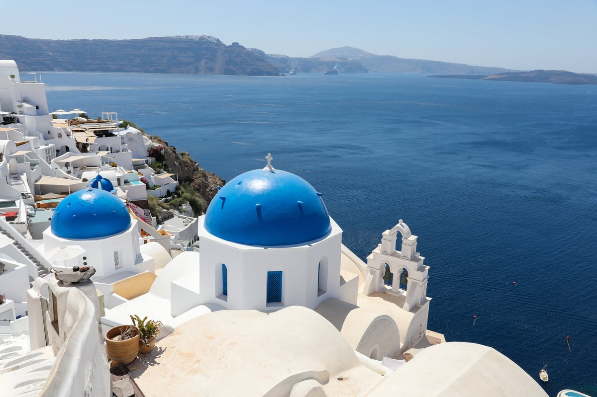 Iconic blue dome churches in Oia Santorini with whitewashed buildings overlooking the caldera