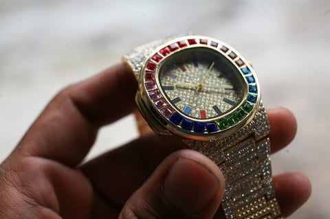 Gold luxury wristwatch with multicolored baguette-cut stones