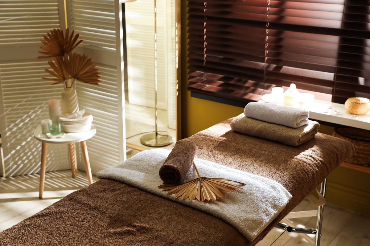 Massage table with supplies near window in stylish spa center
