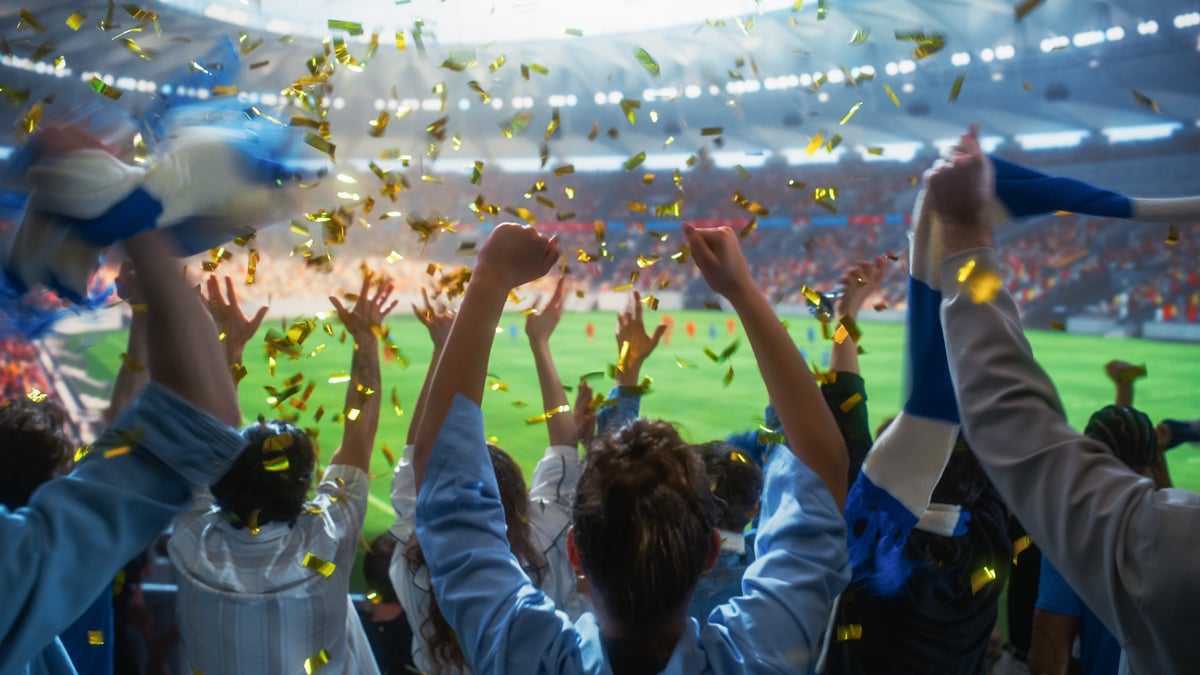 Golden Confetti Falling Over a Diverse Crowd of Excited Soccer Fans With Raised Fists Celebrating