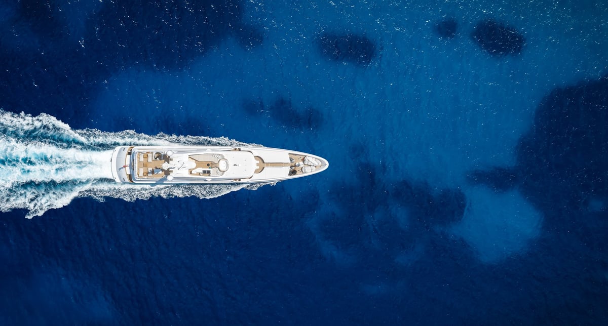 Aerial overhead view of a modern luxury yacht sailing over the blue ocean