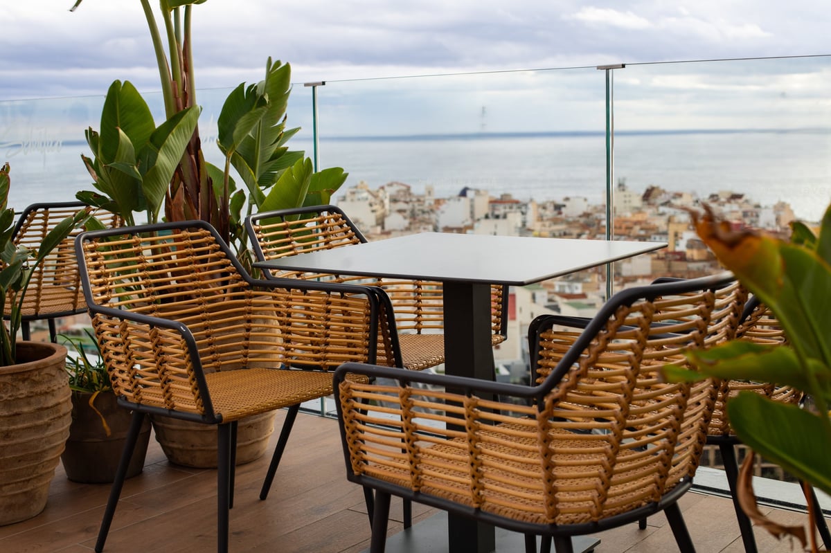 A serene outdoor cafe setting features woven rattan chairs and a dark table