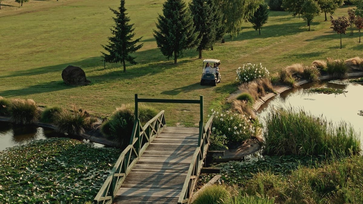 Aerial drone shot of wooden bridge crossing scenic ponds on lush golf course