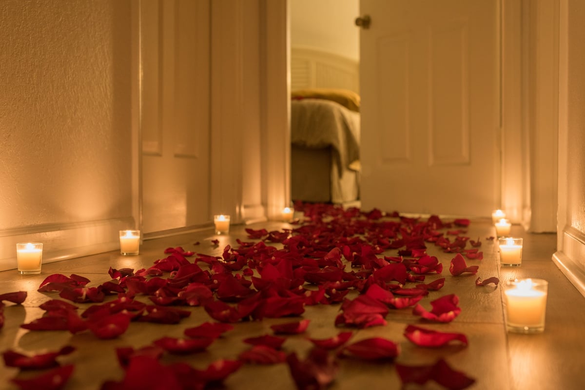 Warm candlelit hallway with rose petals leading to a romantic bedroom