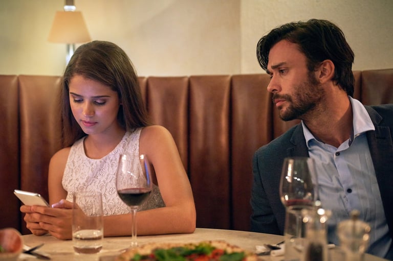 Young woman checking phone on dinner date with her boyfriend