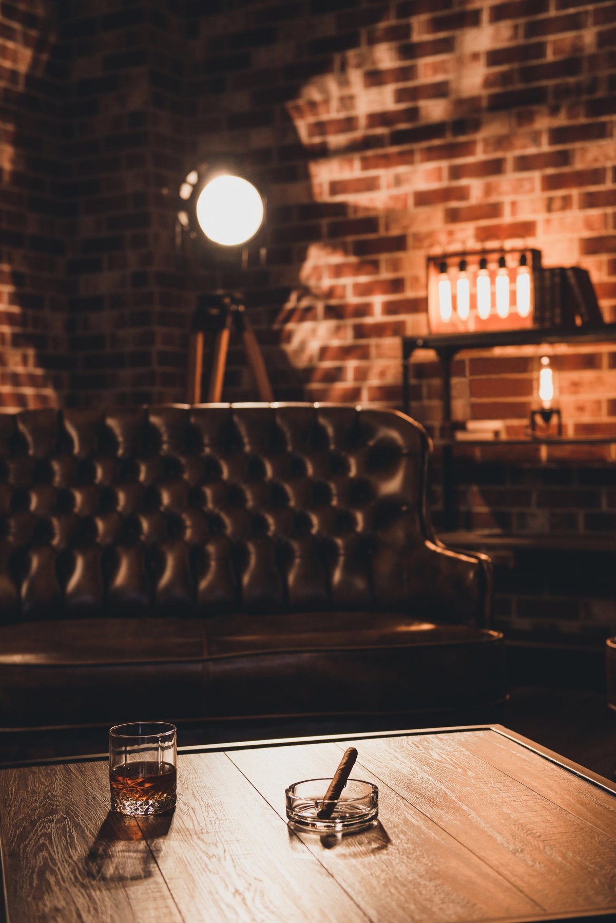 Loft interior. Leather couch with glass of whiskey and cigar on table