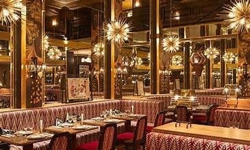 Upscale restaurant interior with burgundy booths, golden pendant lights, wood paneling, and elegant Art Deco design