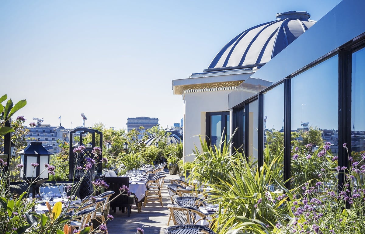 Rooftop terrace with striped blue dome, potted plants, seating area, and city skyline view