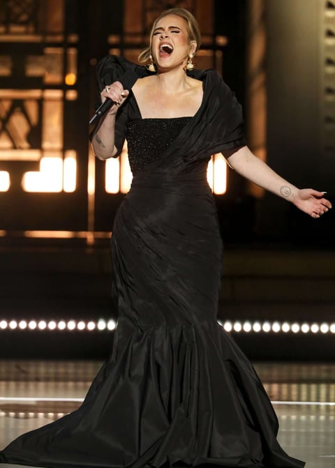 Woman performing on stage in an elegant black gown, holding a microphone