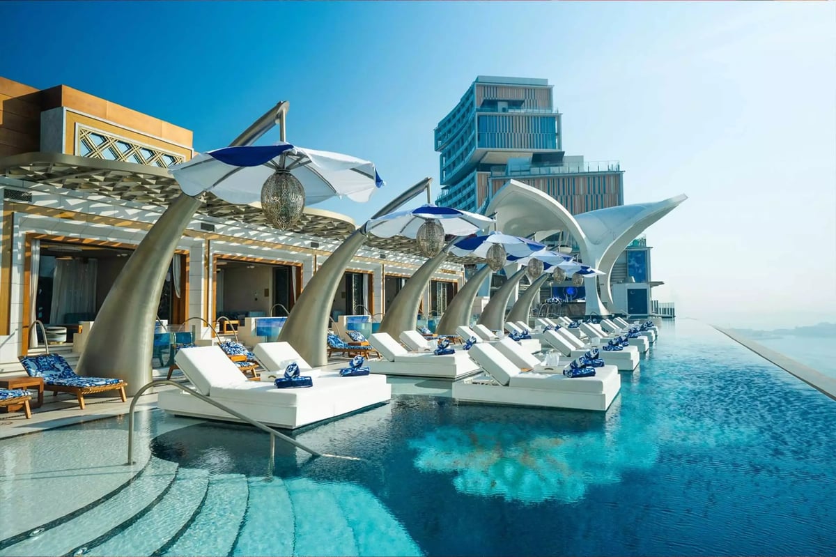 Luxury overwater resort with modern architecture, lounge chairs, and waterslides overlooking turquoise ocean