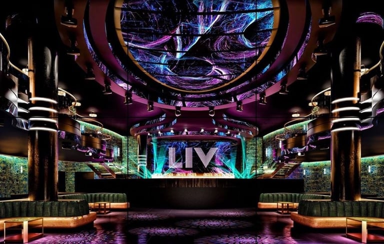 Modern nightclub interior with neon lighting, stage display, and symmetrical design featuring purple and blue LED accents