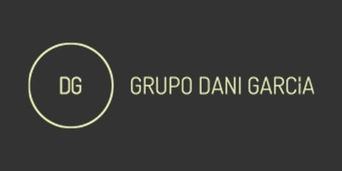 DG Grupo Dani Garcia logo with circular emblem on dark gray background