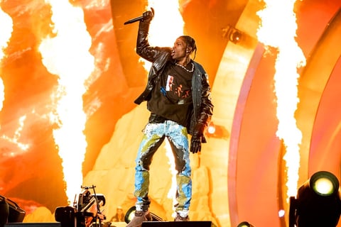Performer on stage with microphone against large orange flame backdrop