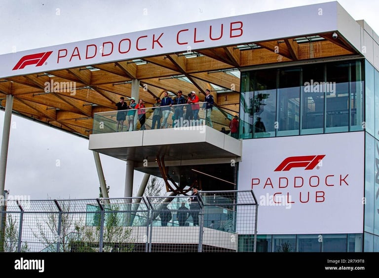Paddock Club viewing structure with F1 branding, featuring spectators on an elevated balcony overlooking a race venue
