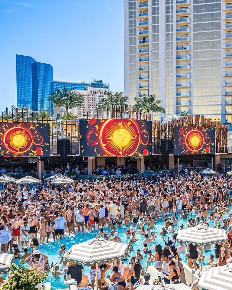 Crowded pool party at resort with LED sun displays and guests enjoying turquoise pool