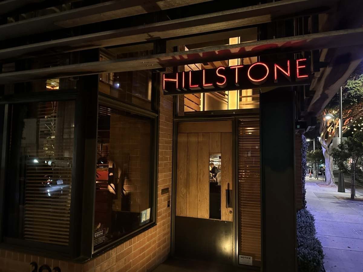 Hillstone restaurant storefront at night with illuminated signage, brick exterior, and glass entrance doors