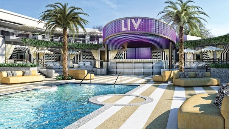 LIV nightclub pool with purple stage, palm trees, lounge seating, and resort-style deck area