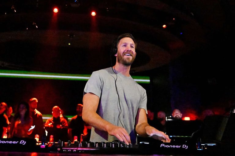DJ performing at turntables in front of a crowd at a nightclub with stage lighting