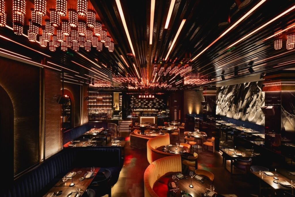 Modern upscale restaurant interior with dramatic linear ceiling lights, red booth seating, and ambient warm lighting