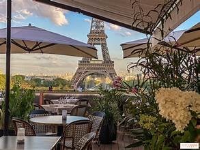 Outdoor rooftop cafe with plants and umbrellas overlooking the Eiffel Tower in Paris